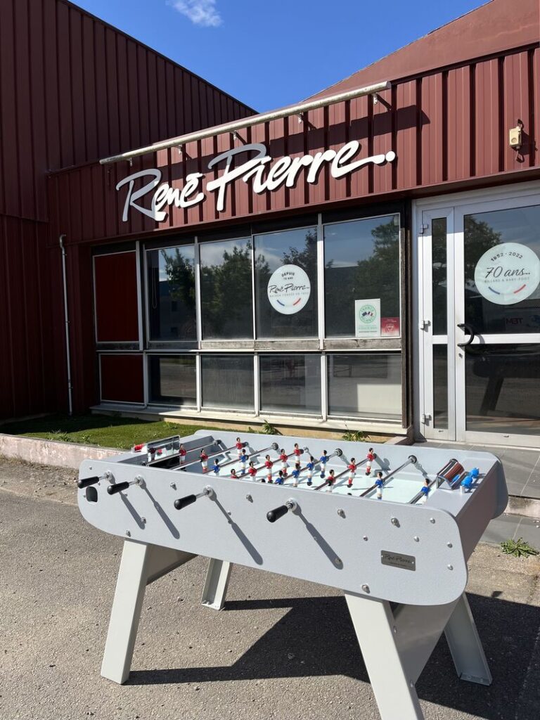 Employé de René Pierre posant avec un modèle de billard dans un cadre professionnel
